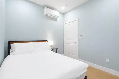 a white bedroom with a bed and a door at 2393 Bonaccord Dr - Mattamel in Vancouver