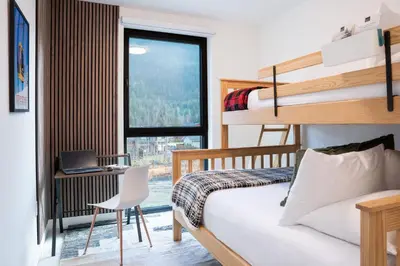 a bedroom with a bunk bed and a desk with a laptop at Wooley Terrace by Revelstoke Vacations in Revelstoke