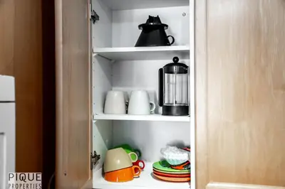 a cupboard with a tea pot and cups and plates at The Breakfast Club Suite - KingBed& AC - Patio - UG Park in Edmonton