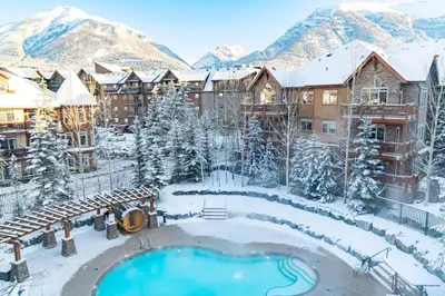 a resort with a swimming pool in the snow at Peaceful 1BR Condo with Hot Tub and Pool in Canmore