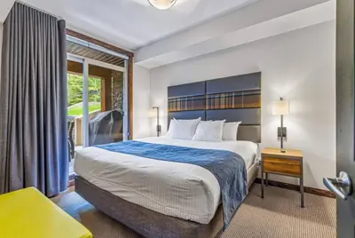 a bedroom with a large bed and a window at Peaceful 1BR Condo with Hot Tub and Pool in Canmore
