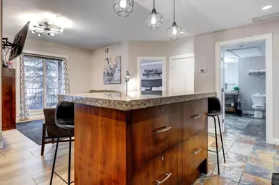 a kitchen with a counter and chairs in a room at Silver Creek 2BR Bliss Hot Tub Access MTN Views in Canmore