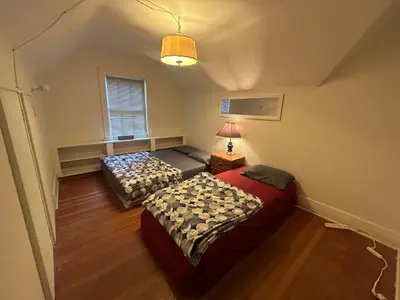 two beds in a small room with a window at Vancouver Budget Guesthouse - Free Parking, Fast WiFi, Near Airport & Downtown in Vancouver