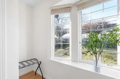 a white room with a window with a plant in a vase at NEW Roomy 3BR Family Suite. 5 min to Skytrain. in Vancouver