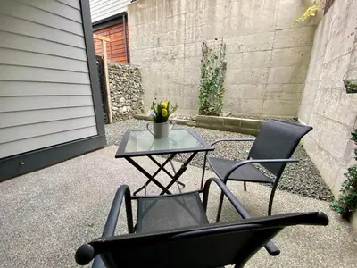 a patio with two chairs and a table with flowers at Ridge Pointe Retreat Your Victoria Hideaway in Colwood