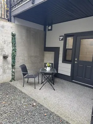 a patio with a table and a chair next to a building at Ridge Pointe Retreat Your Victoria Hideaway in Colwood