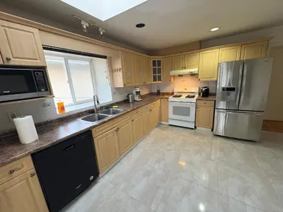 a kitchen with wooden cabinets and a stainless steel refrigerator at Vancouver Budget Stay- Free Parking, Fast WiFi, Near Airport & Downtown 15 Min in Vancouver