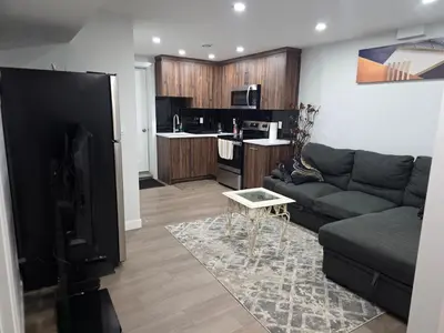 a living room with a couch and a kitchen at YYC Cozy Suites in Calgary