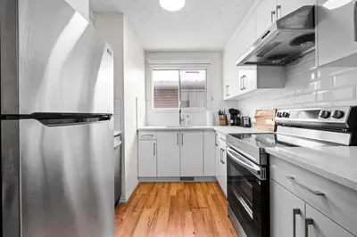 a kitchen with white cabinets and a stainless steel refrigerator at Quiet & Modern Calgary Stay, Prime Location Near YYC, Free Parking in Calgary