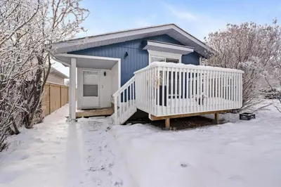 a blue house with a white porch in the snow at Quiet & Modern Calgary Stay, Prime Location Near YYC, Free Parking in Calgary
