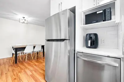 a stainless steel refrigerator in a kitchen with a table at Quiet & Modern Calgary Stay, Prime Location Near YYC, Free Parking in Calgary