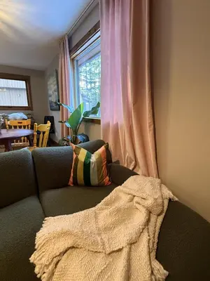 a couch with a blanket on it next to a window at Private 2BR Forest Suite in Bragg Creek with Hot tub, pond, 17 acres of trails in Bragg Creek
