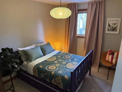 a bedroom with a bed and a window and a lamp at Private 2BR Forest Suite in Bragg Creek with Hot tub, pond, 17 acres of trails in Bragg Creek