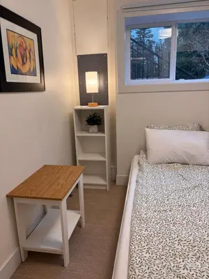 a small bedroom with a bed and a table at Sumas Mountain basement suite in Abbotsford