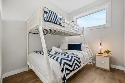 a white bunk bed in a bedroom with a window at Herron Rise Luxury 4 Bedroom Main Floor in Calgary