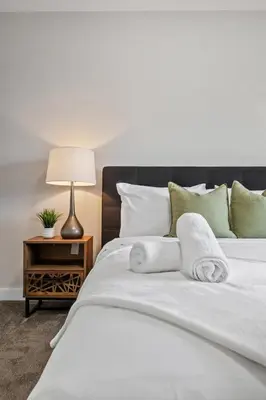 a bedroom with a white bed with towels on it at Herron Rise Luxury 4 Bedroom Main Floor in Calgary