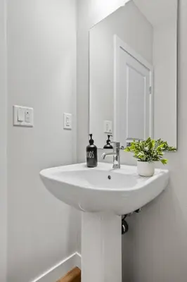 a white sink in a bathroom with a mirror at Herron Rise Luxury 4 Bedroom Main Floor in Calgary