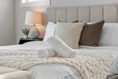 a bedroom with a bed with towels on it at Herron Rise Luxury 4 Bedroom Main Floor in Calgary