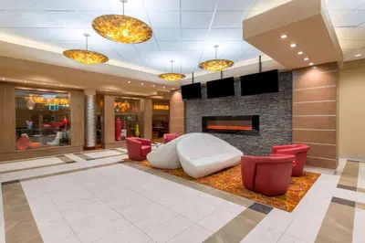 a lobby with a fireplace and red chairs at Hotel 11, MOD A Sonesta Collection in Calgary