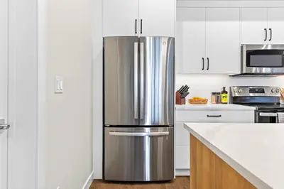 a stainless steel refrigerator in a kitchen with white cabinets at Tranquil 2BR Golden Oasis BBQ, Balcony, MTN Views in Golden