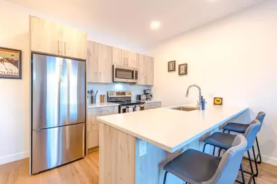 a kitchen with a stainless steel refrigerator and cabinets at Modern 2BR in Golden w/ Stunning MTN Views! in Golden