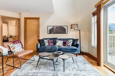 a living room with a blue couch and a table at Cozy 2 BR Condo plus Gym with Stunning Mountain View in Canmore