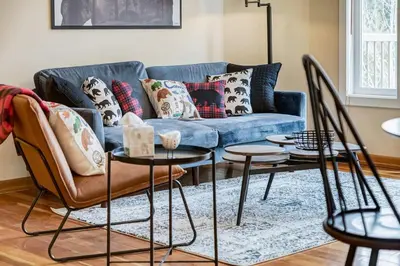 a living room with a blue couch and two tables at Cozy 2 BR Condo plus Gym with Stunning Mountain View in Canmore