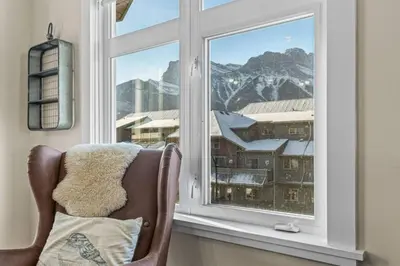 a window with a chair and a view of a mountain at Mountain View Retreat Elegant 3BR condo with Gym in Canmore