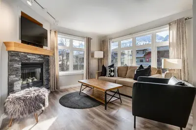 a living room with a couch and a fireplace at Charming 2BR Condo with Spectacular Mountain Views in Canmore
