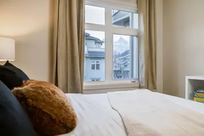 a bedroom with a bed and a large window at Charming 2BR Condo with Spectacular Mountain Views in Canmore