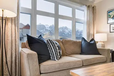 a living room with a couch and a large window at Charming 2BR Condo with Spectacular Mountain Views in Canmore