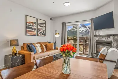 a living room with a couch and a table with flowers at Rockies Getaway Condo With Mountain View in Canmore