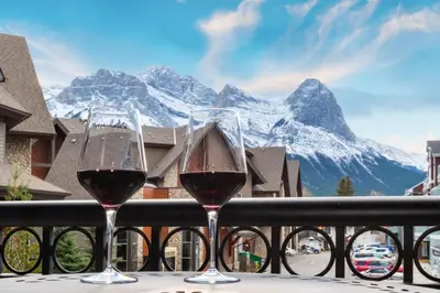 two glasses of wine sitting on a balcony with a mountain at Renovated Haven in Rockies with Hot Tub and Pool in Canmore