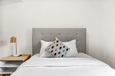 a bed with a gray headboard and two pillows at Splendid Mountain View 2BR Condo with Pool and Hot Tub in Canmore
