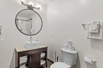 a white bathroom with a sink and a mirror at Splendid Mountain View 2BR Condo with Pool and Hot Tub in Canmore