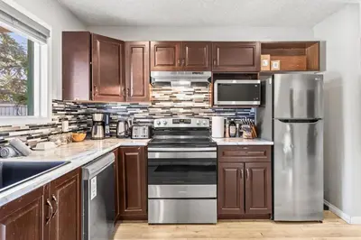 a kitchen with wooden cabinets and a stove top oven at 2BR Bow Valley Retreat with BBQ Near Parks and Banff in Canmore