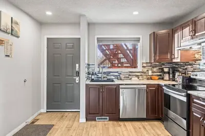 a kitchen with wooden cabinets and a gray door at 2BR Bow Valley Retreat with BBQ Near Parks and Banff in Canmore