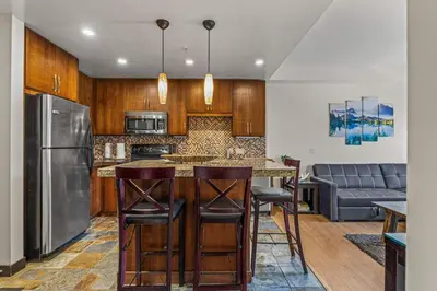 a kitchen with wooden cabinets and a bar with bar stools at Relaxing 1BR Getaway Hot tub plus Amazing Mtn Views in Canmore
