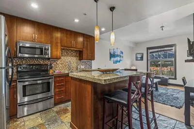 a kitchen with wooden cabinets and a island with bar stools at Relaxing 1BR Getaway Hot tub plus Amazing Mtn Views in Canmore