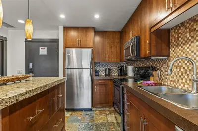 a kitchen with wooden cabinets and a stainless steel refrigerator at Relaxing 1BR Getaway Hot tub plus Amazing Mtn Views in Canmore