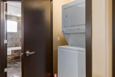 a washer and dryer in a bathroom with a door at Cozy Rocky Mountain Studio with Hot tub and Gym in Canmore
