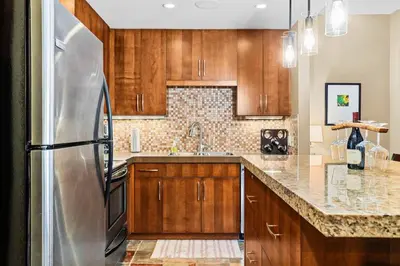 a kitchen with wooden cabinets and a stainless steel refrigerator at Ideal 2BR Canmore Haven Hot Tub plus Stunning Views in Canmore