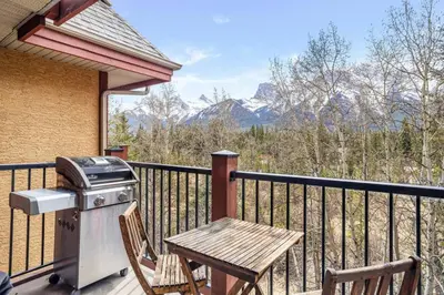 a grill and a picnic table on a balcony with mountains at Peaceful 2BR Retreat with MTN Views Close to Banff in Canmore