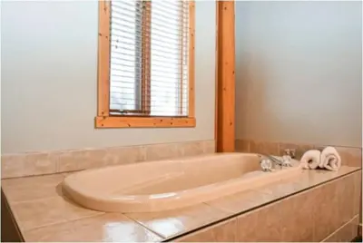 a bathroom with a large tub with a window at Charming Rustic Cabin Perfect for Groups in Golden