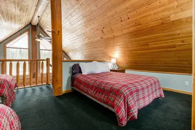 a bedroom with two beds and a wooden wall at Beautiful Rustic Chalet in the Heart of Rockies in Golden