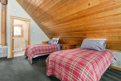 two beds in a room with a wooden wall at Beautiful Rustic Chalet in the Heart of Rockies in Golden