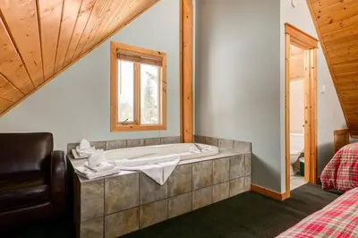 a bathroom with a bath tub with a window at Beautiful Rustic Chalet in the Heart of Rockies in Golden