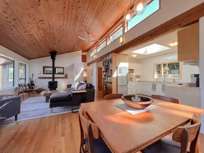 a kitchen and living room with a wooden table at Marielles Lookout - Your Oceanfront Escape Framed by Forest & Waves in Tofino