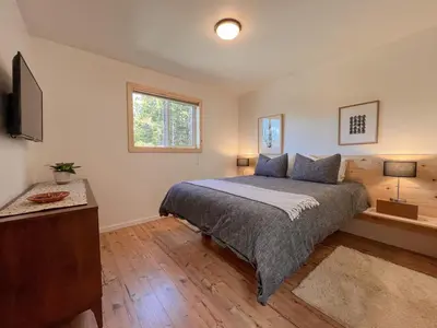 a bedroom with a bed and a television in it at Marielles Lookout - Your Oceanfront Escape Framed by Forest & Waves in Tofino