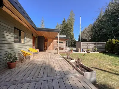 a wooden deck with a yellow bench on a house at Marielles Lookout - Your Oceanfront Escape Framed by Forest & Waves in Tofino